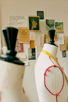 two mannequins sitting next to each other in front of a wall with pictures on it