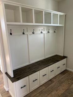 an empty room with white cabinets and wooden bench in the center, on hard wood flooring