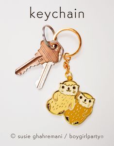 the key chain has two owls on it and is attached to a gold plated keychain