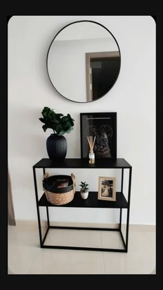 a black shelf with a mirror and plants on it next to a potted plant