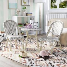 two white wicker chairs sitting next to a small table on top of a rug