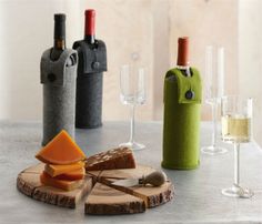 three wine bottles and two cheese slices on a wooden board with corks in the foreground