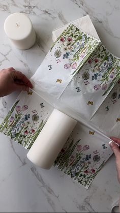 someone is wrapping up some paper on top of a marble table with candles and flowers