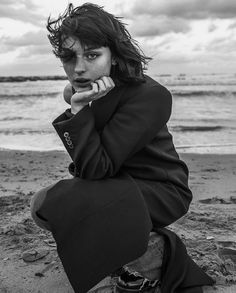 black and white photograph of a woman sitting on the beach with her hand under her chin