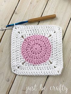 a crocheted square with a pink circle on it next to a knitting needle