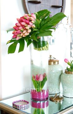 flowers are in vases on a glass table