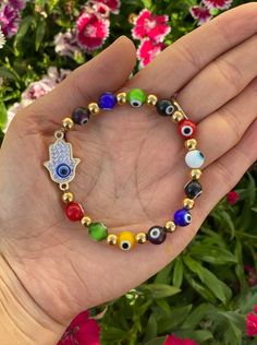 The Multi color Evil Eye Charm Bracelet is perfect for those who wish to be protected always. An Evil Eye is one of the most powerful symbols in the world, and the Multi color charm bracelets are made with various colored eyes to bring you protection from various kinds of evil. The bracelet features a hand-hamsa adorned with rhinestones and at the center the traditional blue evil eye, which brings good luck and protection to its wearer. This Evil Eye is cast with an intent to protect by warding Colorful Adjustable Spiritual Jewelry, Symbolic Multicolor Beaded Bracelets As Gift, Symbolic Multicolor Round Beads Bracelets, Symbolic Multicolor Round Beads Bracelet, Symbolic Multicolor Beaded Jewelry, Symbolic Multicolor Beaded Bracelets With Round Beads, Symbolic Multicolor Beaded Bracelets, Spiritual Multicolor Good Luck Jewelry, Spiritual Multicolor Bracelets As Gifts