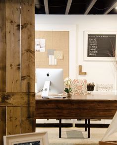 a desk with a computer on top of it in front of a wooden paneled wall