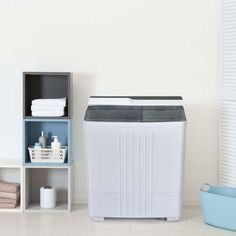 a small washing machine sitting next to a shelf