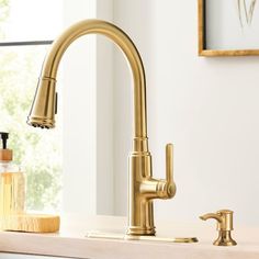 a gold faucet with soap dispenser next to it on a counter