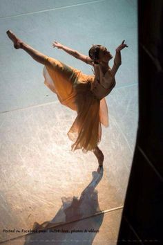 a ballerina is performing on the floor with her arms stretched out and legs spread wide