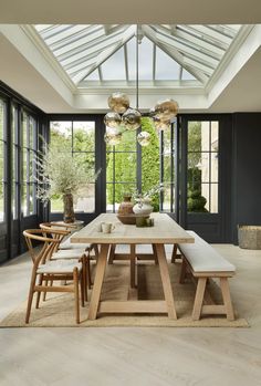 a dining room table with four chairs and a bench in front of the glass windows