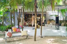 a wooden bench sitting on top of a sandy beach next to palm trees and plants