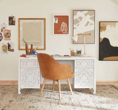 a chair sitting in front of a desk with pictures on the wall