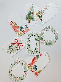 four tags with christmas designs on them sitting next to each other and one has a red bow