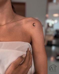 a woman with a half moon tattoo on her left arm and chest, holding onto a white dress