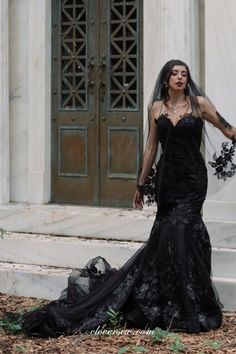 a woman in a black wedding dress standing on the steps with her arms out and hands behind her back