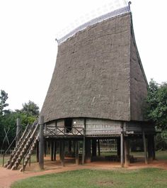 an old building with a thatched roof and stairs leading up to the top floor