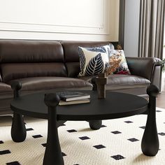 a living room with a couch, coffee table and pillows on the floor in front of a window