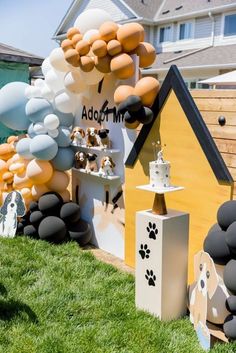 a dog themed birthday party with balloons, cake and decorations on display in front of a house