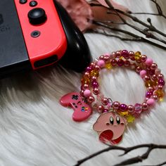 If you are a fan of classic video games, this is the bracelet for you! Each bracelet is designed using memory wire, split rings, glass pearls and glass crystals.  Bracelets are accented with a pink gamer character charm on one side and a pink video game controller on the other. Since bracelets are created using memory wire, they are one size fits all. Lightweight and comfortable. All components used are nickel free. Pink Metal Novelty Jewelry, Novelty Pink Metal Jewelry, Pink Video, Crystals Bracelets, Infinity Wrap, Pink Games, Classic Video, Classic Video Games, Video Game Controller