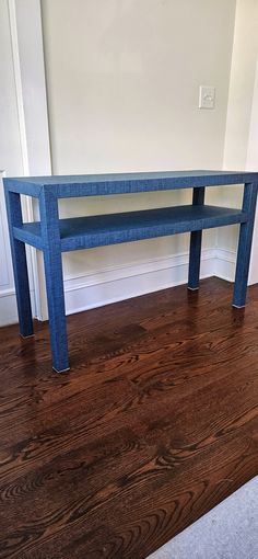 a blue bench sitting on top of a hard wood floor next to a white wall