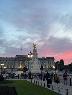 people are walking around in front of the capitol building at dusk with pink and blue skies