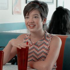 a woman sitting at a table with a drink in her hand