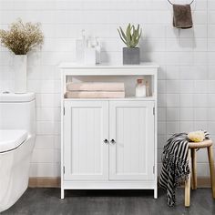 a bathroom with a toilet, sink and white cabinet in the corner on the floor