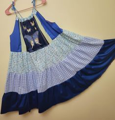 a blue and white dress hanging on a hanger next to a yellow wall,