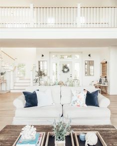 a living room filled with white furniture and lots of pillows on top of it's couches