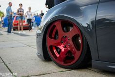 a close up of the rims on a car with people standing around in the background