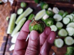 a person holding up a piece of food in their hand next to cucumbers