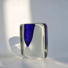 a blue and white glass ring sitting on top of a white table next to a wall