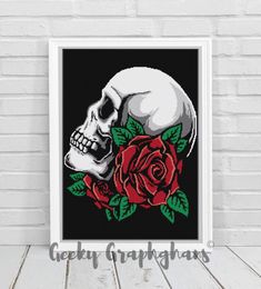 a cross stitch skull and red rose on a black background