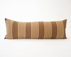 a brown and white striped pillow sitting on top of a white floor next to a wall