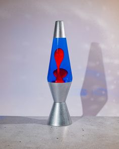 a blue and red vase sitting on top of a cement floor next to a white wall