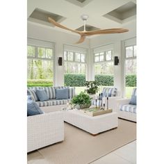 a living room filled with furniture and a ceiling fan in the middle of it's walls