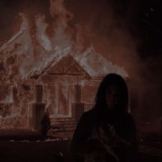 a woman standing in front of a house on fire