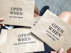 four brown envelopes with words on them are held by someone's legs and feet