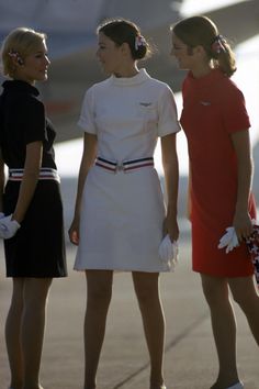 three women standing next to each other in front of an airplane