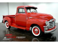 an old red truck parked in a garage