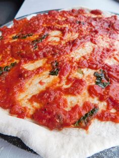 a pizza sitting on top of a pan covered in cheese and tomato sauce, ready to go into the oven