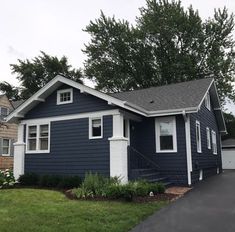 a blue house with white trim on the front and side of it, in a residential neighborhood