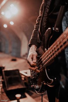 a person playing an electric bass guitar in a room with other musical equipment and lighting