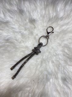 a keychain that is laying on top of a white fur covered surface with beads