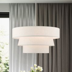 a white chandelier hanging over a dining room table with flowers in the center