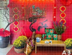 a room filled with vases and plants next to a wall covered in red tiles