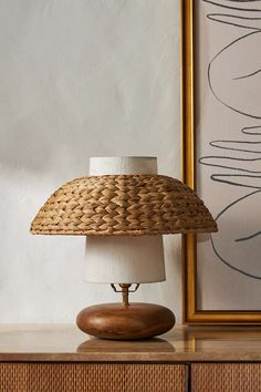 a lamp sitting on top of a wooden table next to a framed photo and painting