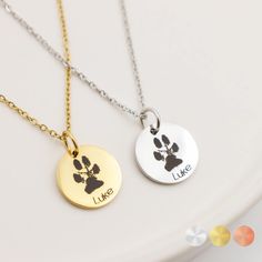 two necklaces with dog paw prints on them, one is gold and the other is silver